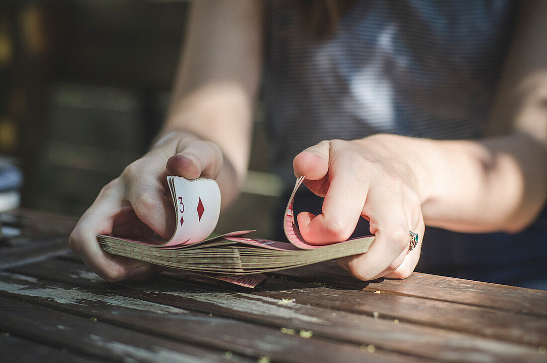 Young Woman's Hands Shuffling Playing Cards Outside