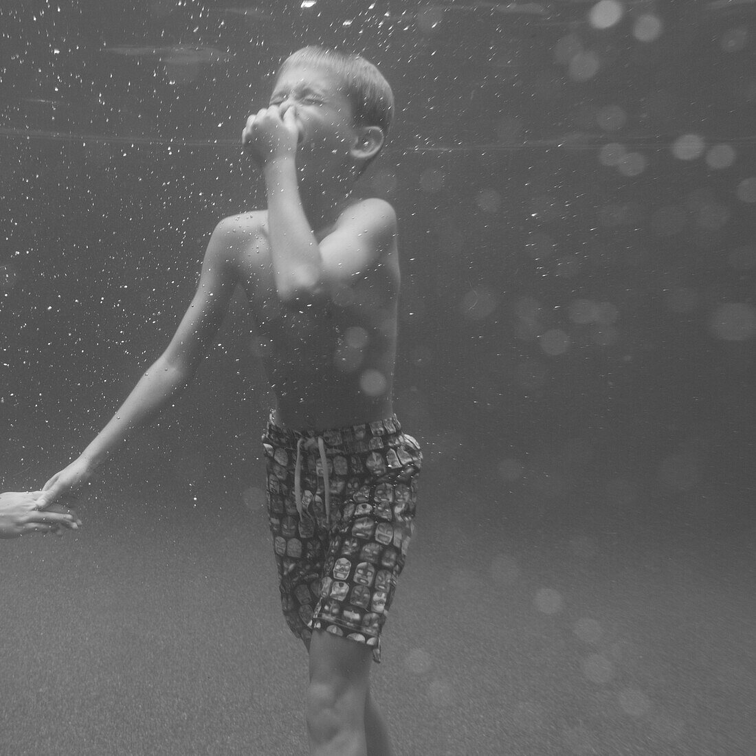 Boy Holding Nose Underwater in Swimming Pool