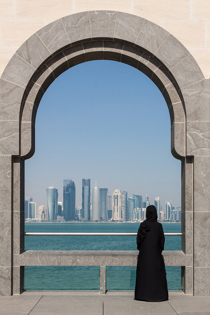 young qatari woman in traditional dress looking at the buildings of the city center from one of the terraces of the museum of islamic art, built by the architect ieoh ming pei, doha, qatar, persian gulf, middle east