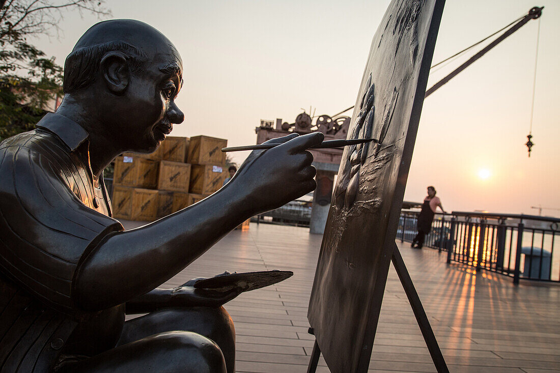 sculpture in bronze recalling the countryÆs history and skyscrapers, tourist walk on the promenade of asiatique the riverfront near the chao phraya river, bangkok, thailand, asia