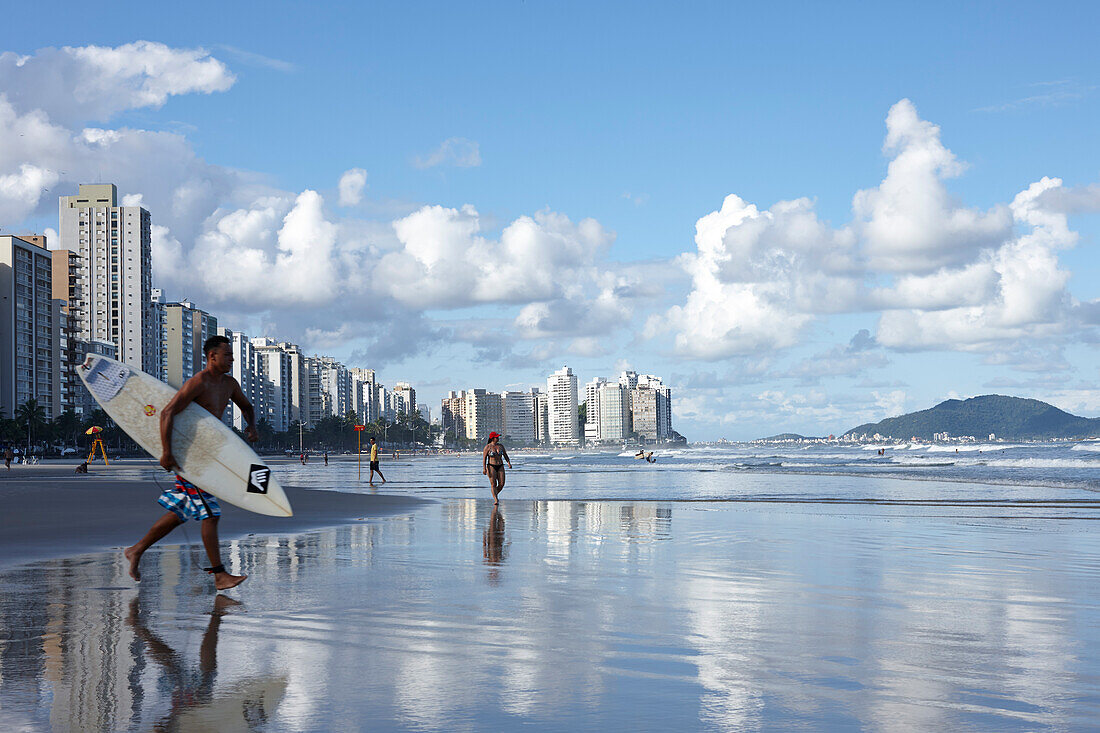 Surfer vor Appartementhäusern am Strand, Praia das Asturias, Stadtstrand, in Guaruja, Costa Verde, Sao Paulo, Brasilien