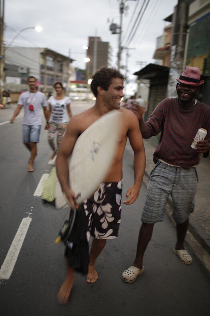 Surfer kommen abends vom Strand an der Avenida Oceanica, Stadtteil Barra, Salvador de Bahia, Bahia, Brasilien