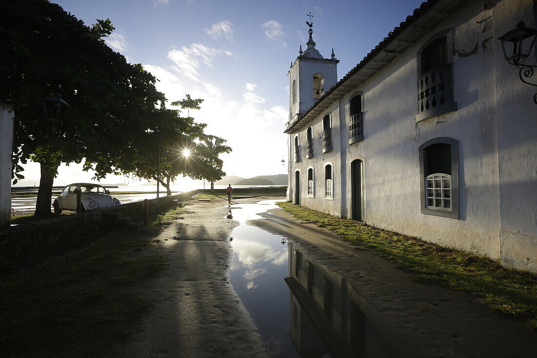 Morning sun in the rain filled Rua de Chapala, curch Iglesia de Nostra Senora das Dores, historic old town, Paraty, Costa Verde, Rio de Janeiro, Brazil