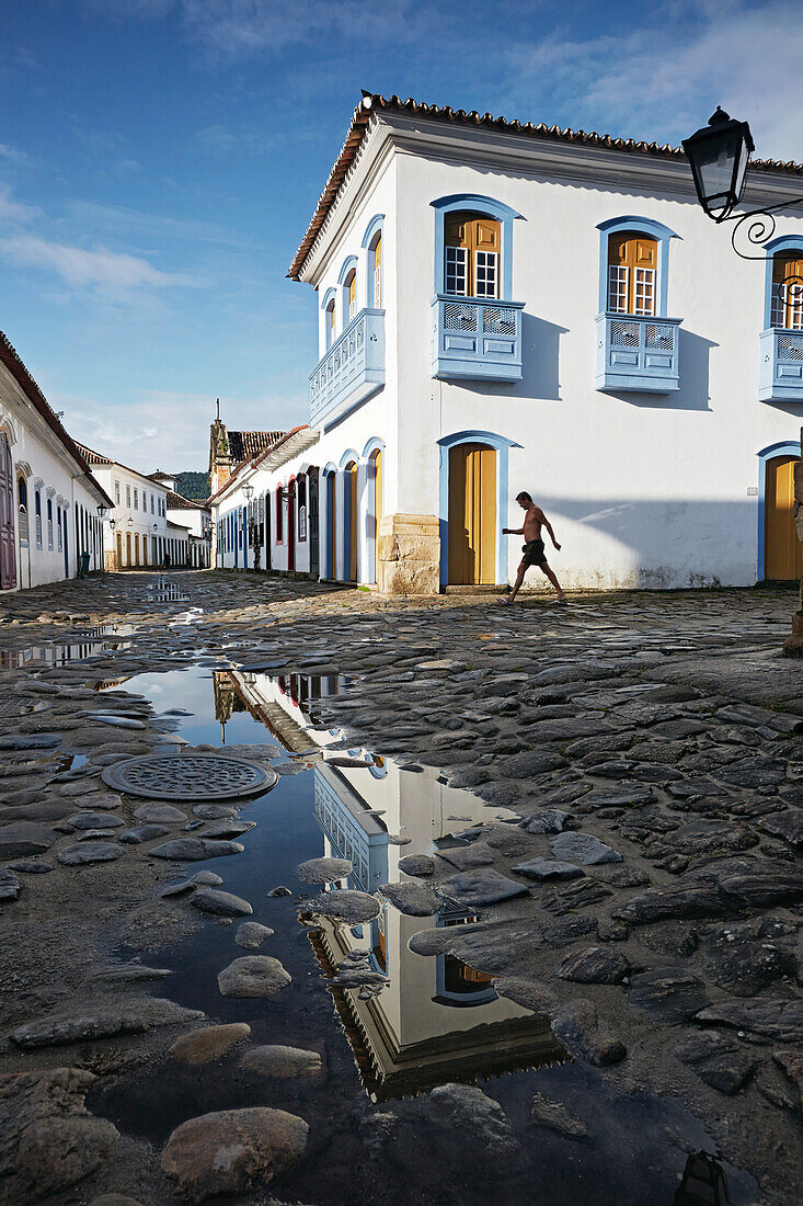 Morning sun in rain filled Rua Marechal Santos Dias, church in the back is Iglesia de Nostra Senora do Rosario, historic old town, Paraty, Costa Verde, Rio de Janeiro, Brazil