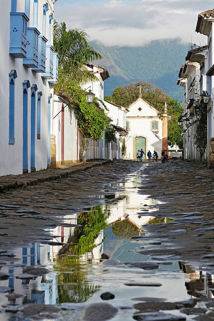 Morning sun in rain filled Rua Samuel Costa, church Iglesia de Nostra Senora do Rosario, historic old town, Paraty, Costa Verde, Rio de Janeiro, Brazil