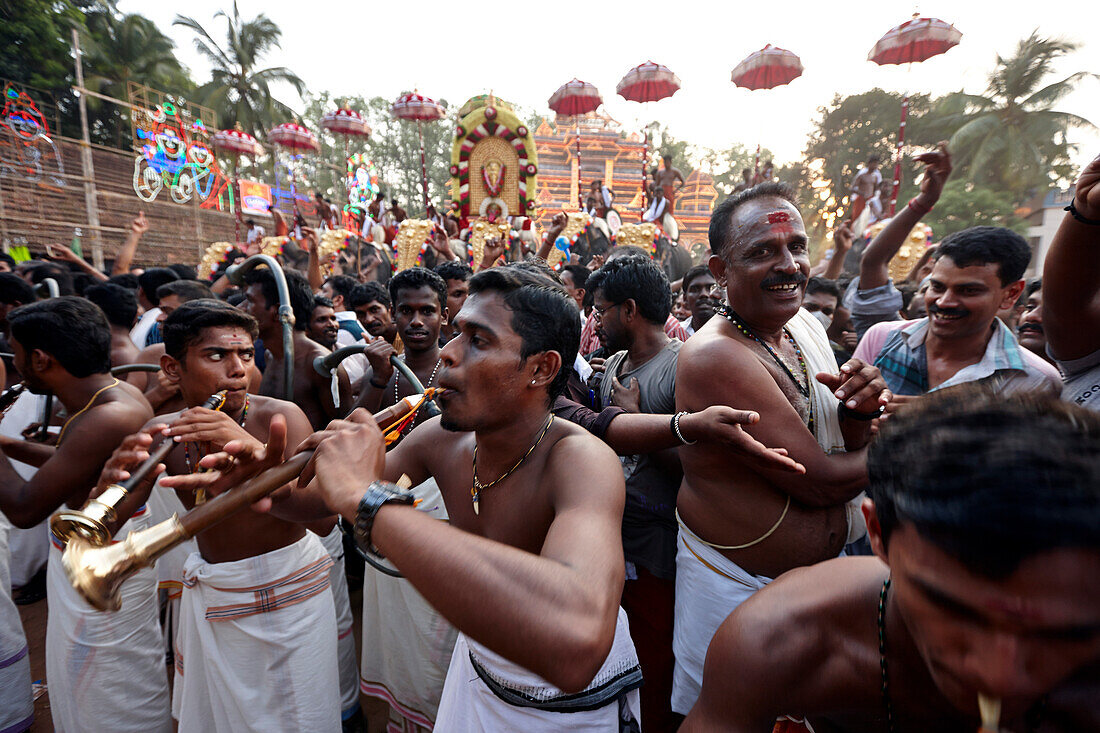Musicians with wind and percussion instruments playing deafening loud with men dancing around them, decorated elephants and illuminated timber scaffolding Aana Pandal, Nemmara Vela, Vela Festival takes place in summer after harvest, Hindu temple festival 