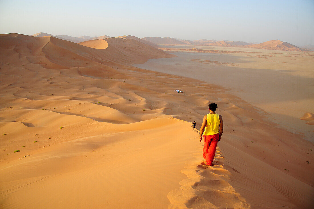 Sultanate of OMAN the Rub al Khali desert, a young lonely man is walking on the edge of a high sand dune