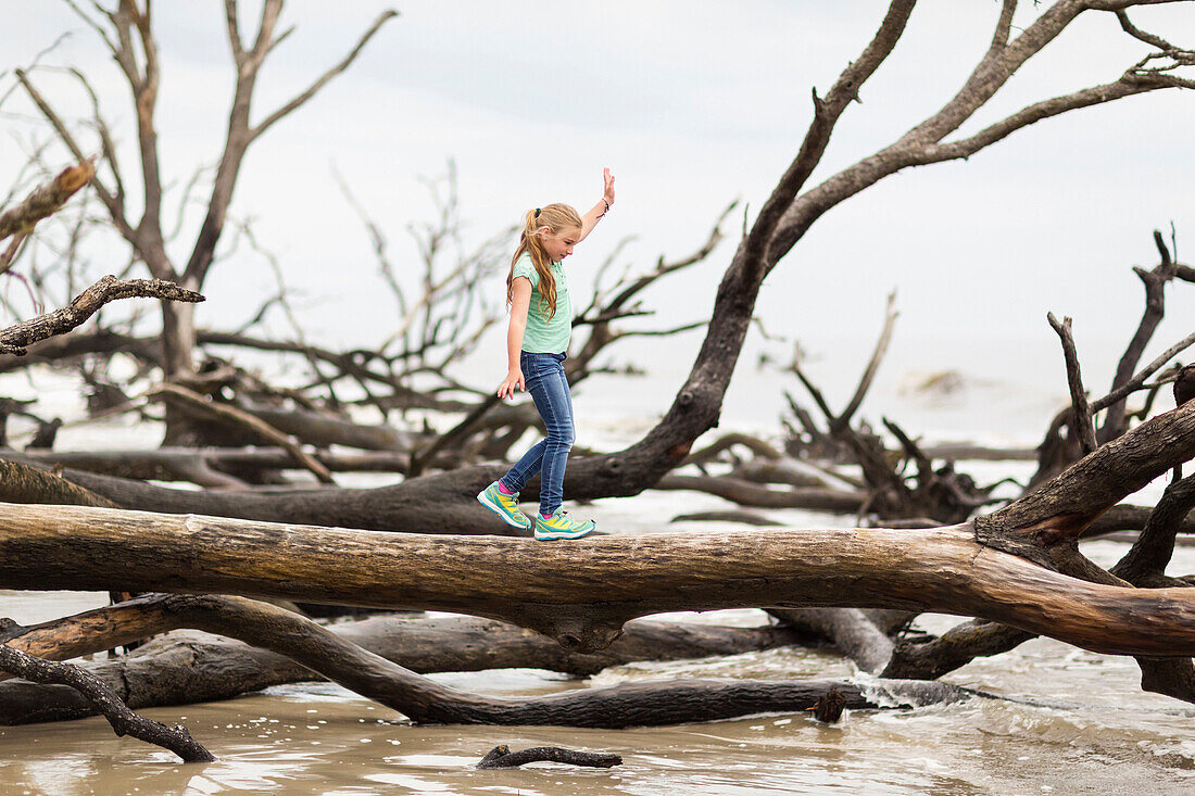 Caucasian girl walking on driftwood tree