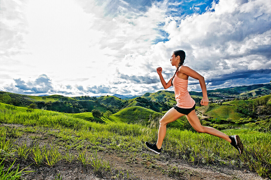 Gemischtrassiger Sportler beim Laufen auf einer ländlichen Hügelkuppe