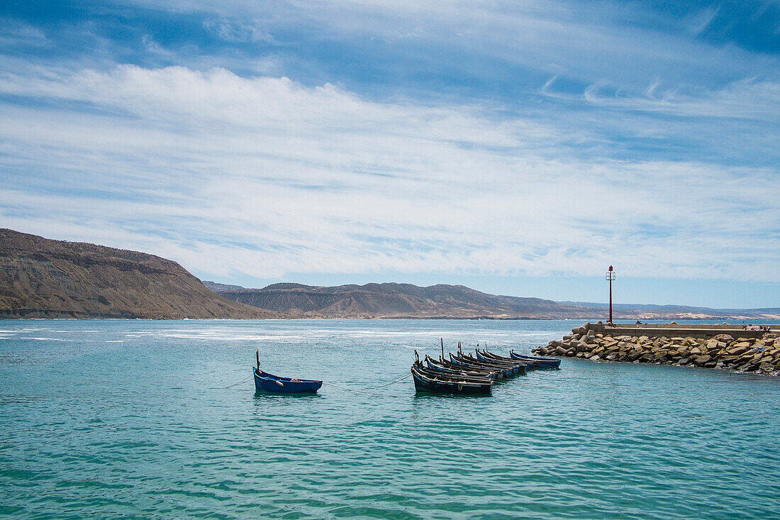 Boats docked on rocky pier in remote harbor