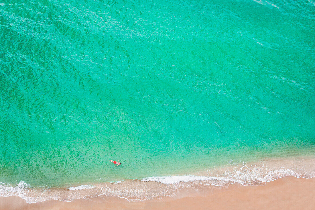 Aerial view of Caucasian man swimming in ocean on beach