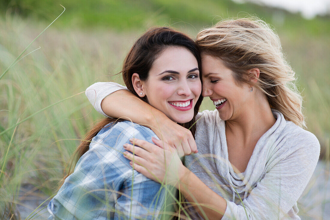 Smiling women hugging on beach – License image – 71066164 lookphotos