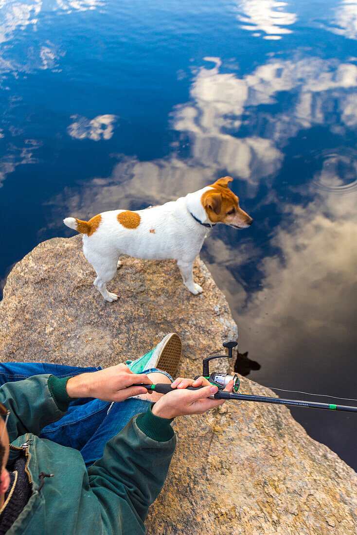 Caucasian man fishing with dog in remote lake