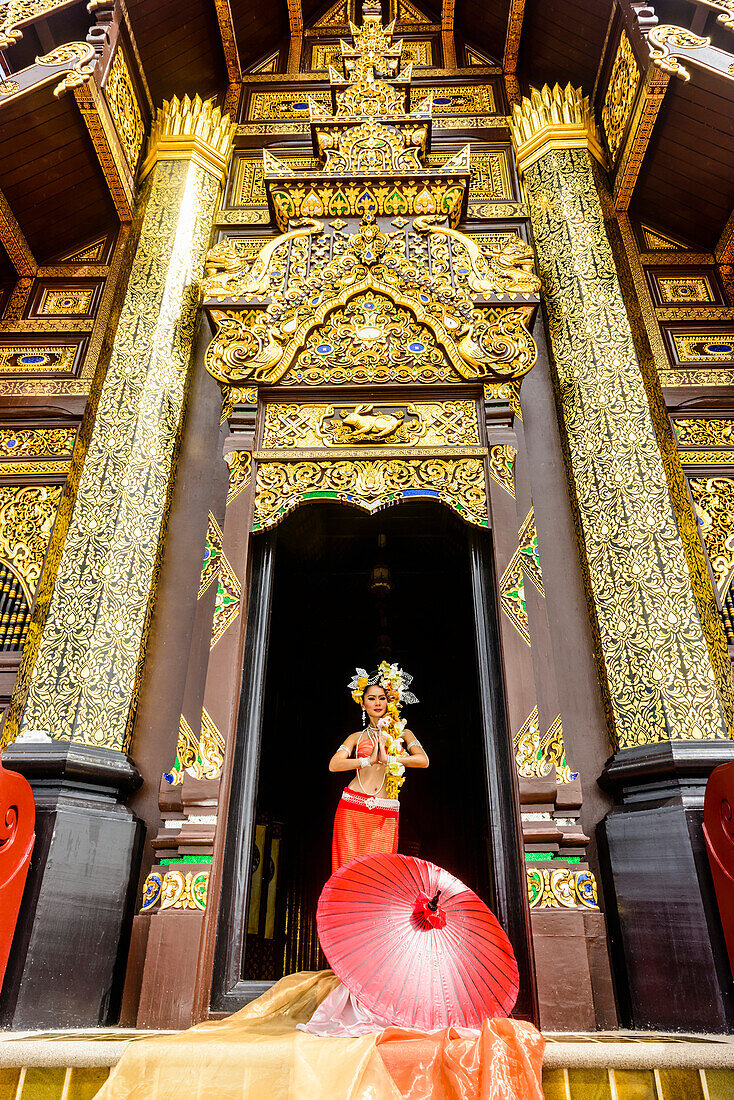 Asian woman standing in ornate temple doorway, Chiang Mai, Chiang Mai, Thailand