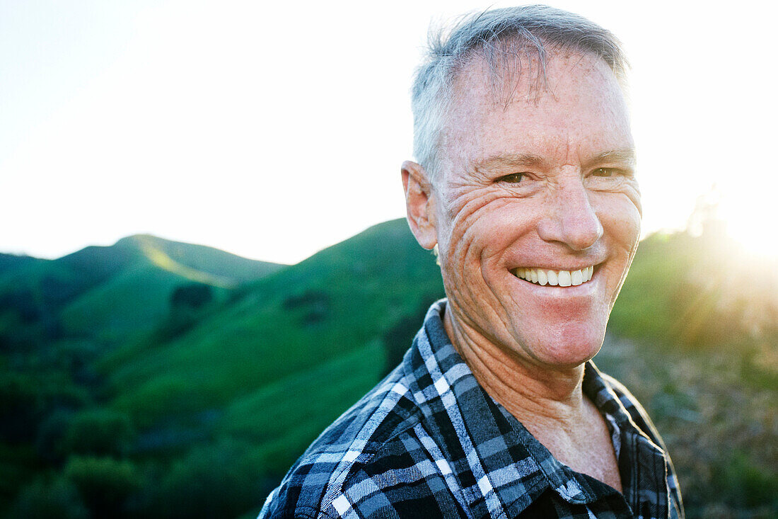 Older Caucasian man smiling on rural hilltop