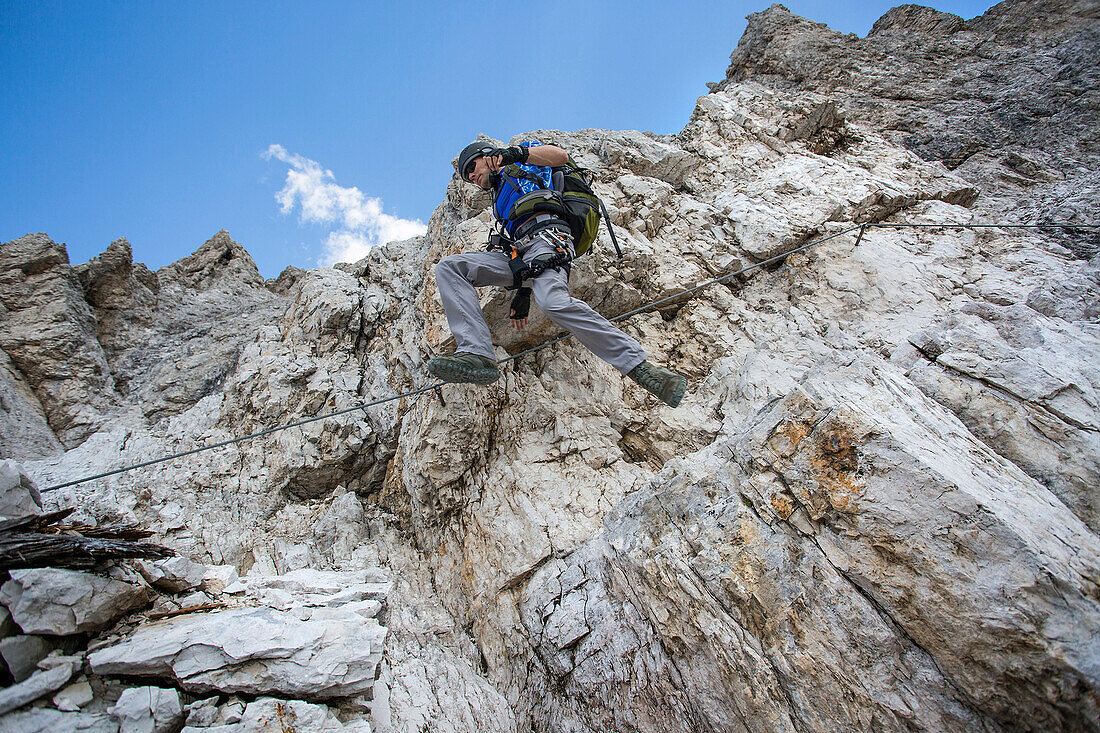 Low angle view of Caucasian climber scaling remote mountain slope