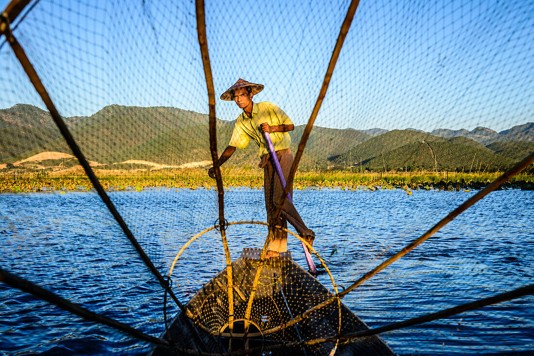 Asian fisherman using fishing net in canoes on river