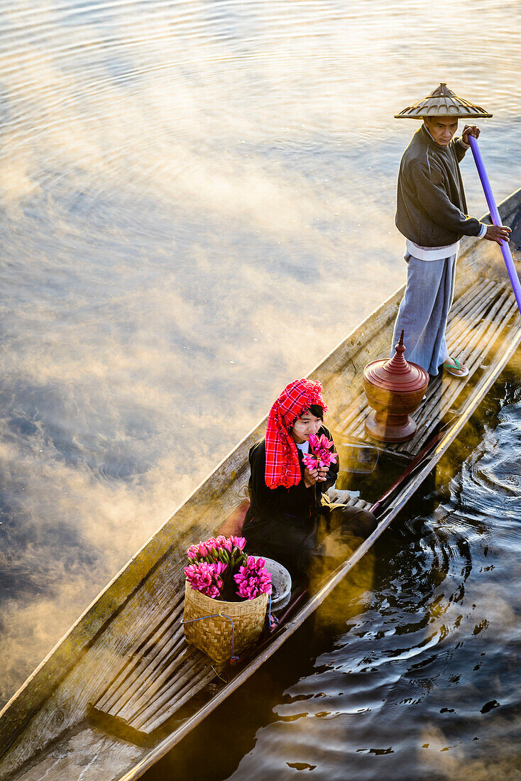 Asian farmer and daughter rowing in canoe on river
