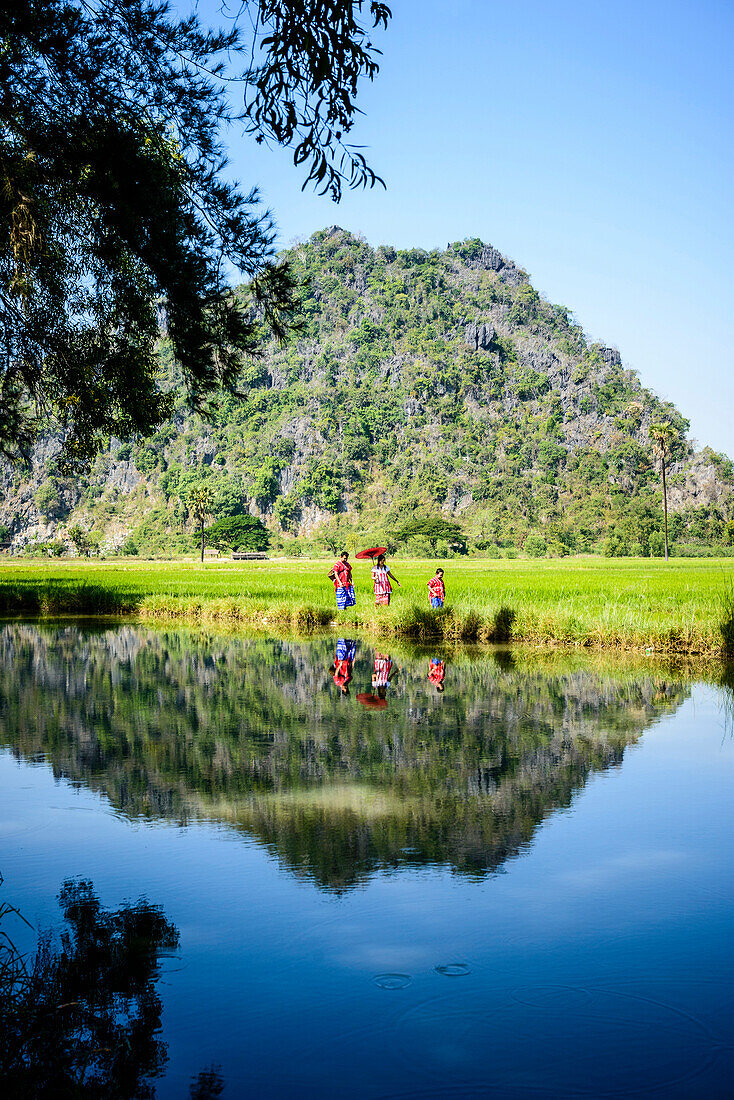 Asian family walking past still lake in rural field