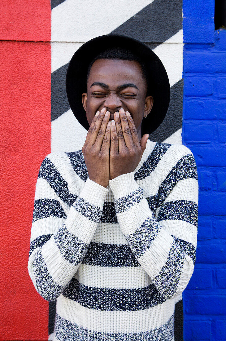 Black man laughing near colorful wall