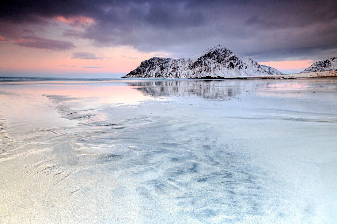 Sunset on Skagsanden beach surrounded by snow covered mountains reflected in the cold sea, Flakstad, Lofoten Islands, Arctic, Norway, Scandinavia, Europe