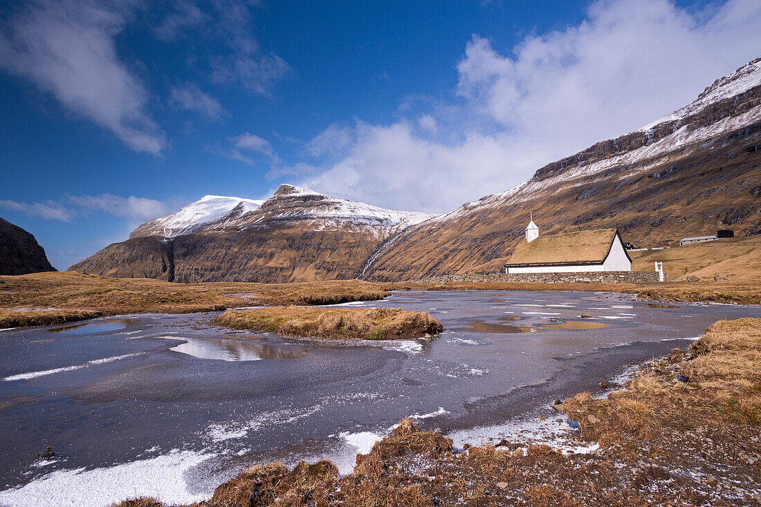 Spectacular mountain scenery surrounding Saksun and pretty turf roofed church, Streymoy, Faroe Islands, Denmark, Europe