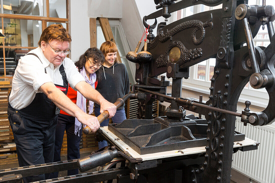 Museum of Printing Arts Leipzig, worker and visitors at the printing machine, type foundry, Leipzig, Saxony, Germany