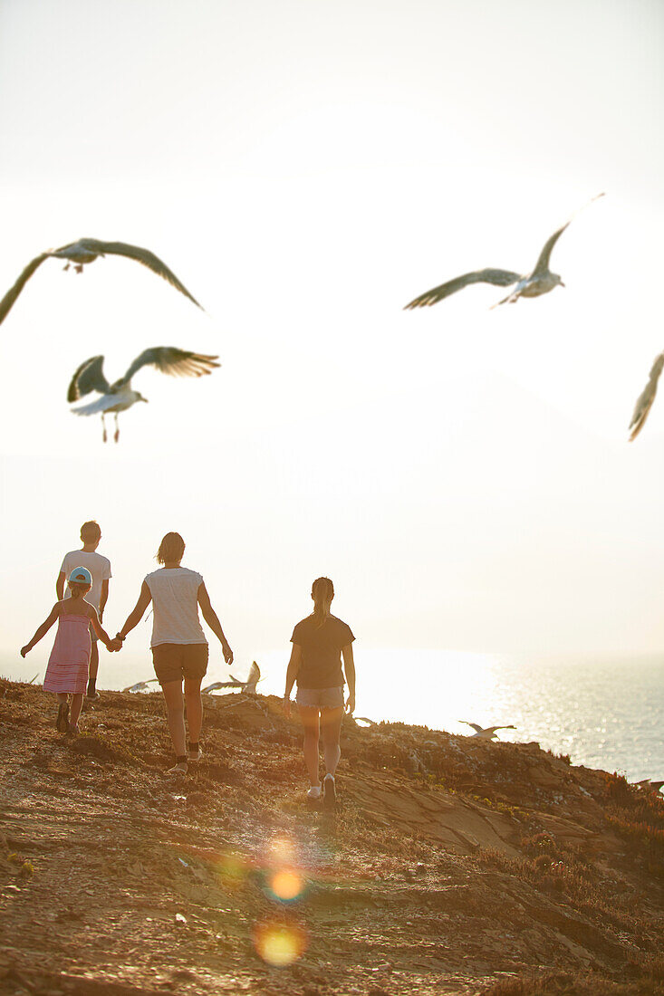 Young family walking along the steep coast, Rota Vicentina, Portugal