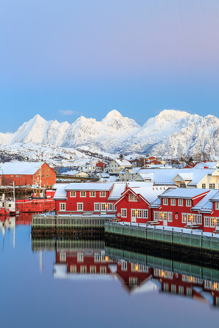 Pink sunset over the typical red houses reflected in the sea, Svolvaer, Lofoten Islands, Arctic, Norway, Scandinavia, Europe