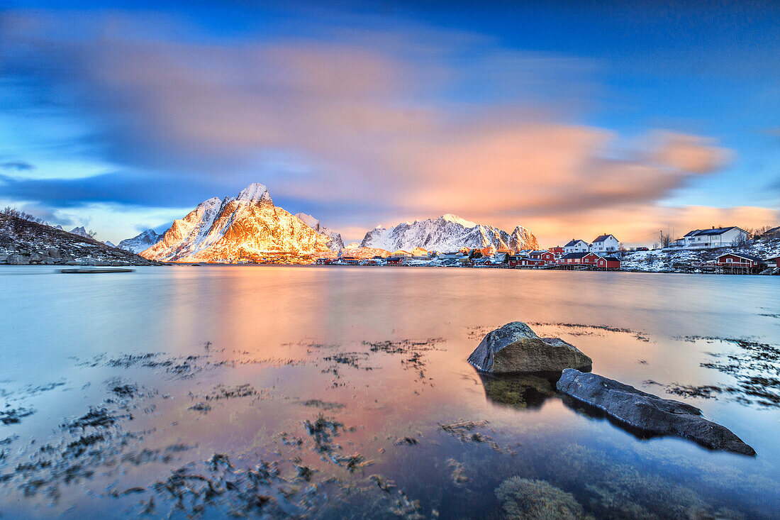 The pink sky at sunrise illuminates Reine village with its cold sea and snowy peaks, Lofoten Islands, Arctic, Norway, Scandinavia, Europe