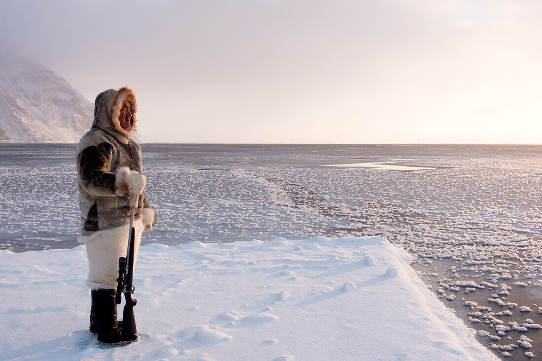 One of the last remaining Inughuit subsistence hunters, Naimanngitsoq Kristiansen, stands on watch with his rifle for marine mammals at the ice edge, Greenland, Denmark, Polar Regions