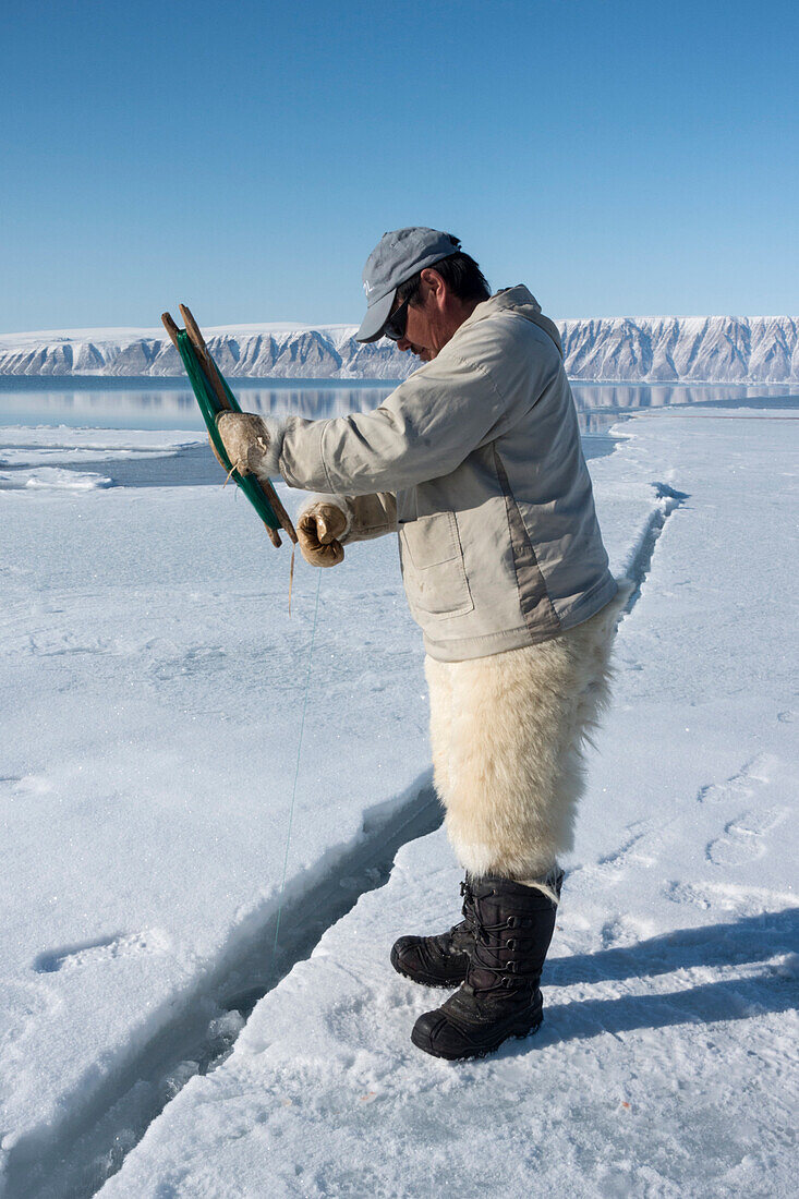 Inuit hunter line fishing at the floe edge for Arctic cod, sculpin and halibut near Herbert Island, Greenland, Denmark, Polar Regions