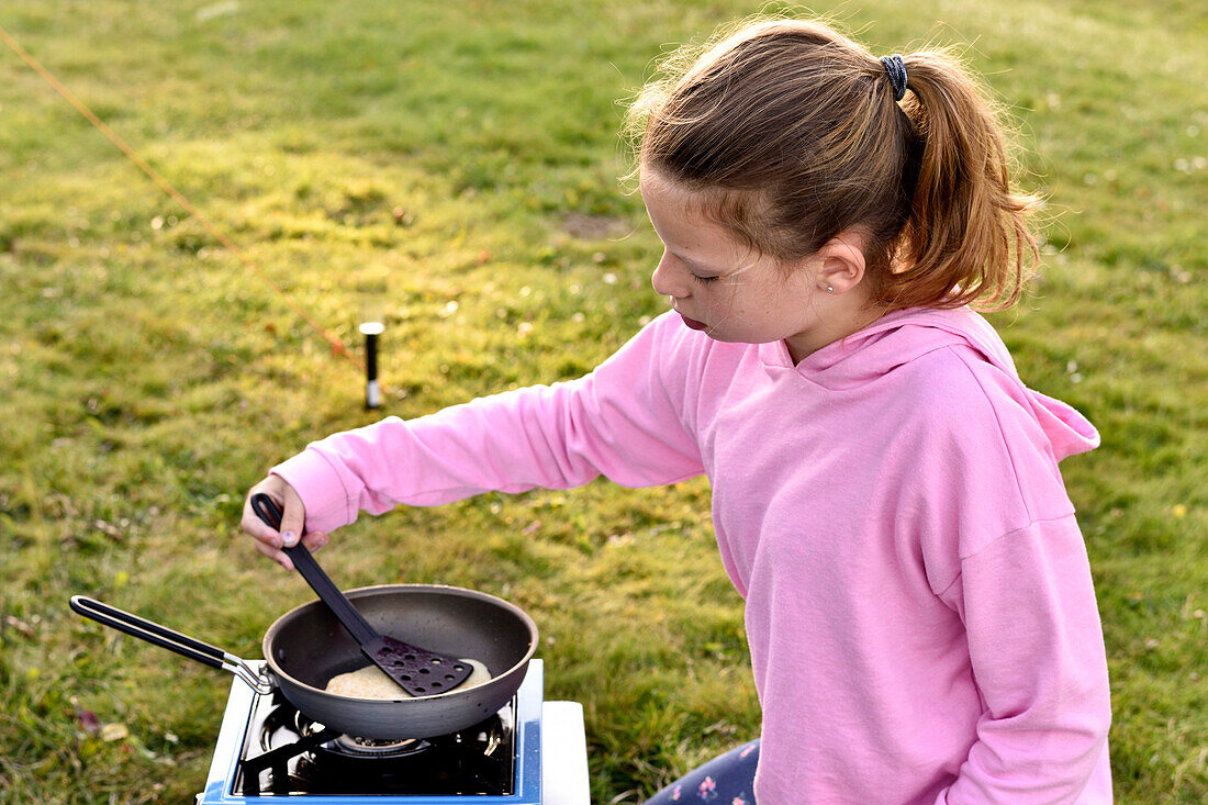 Girl frying pancakes outside, Camping ground, Vaestervik, Smaland, Sweden