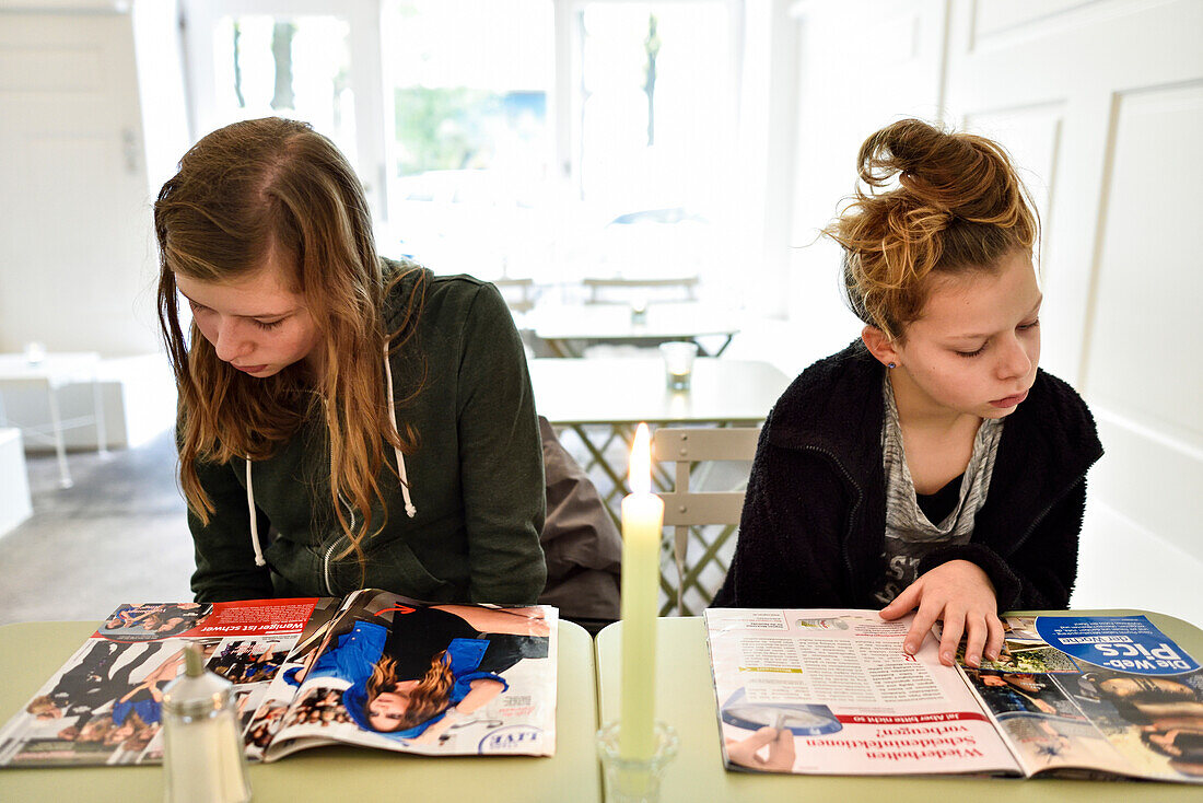 Mädchenlesen Klatschzeitung im Café, München, Bayern, Deutschland, Europa