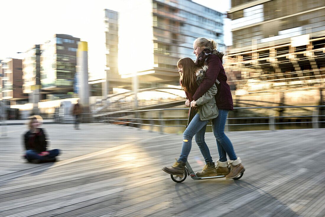 2 girls on a scooter in Hafencity, Hamburg, Germany, Europe