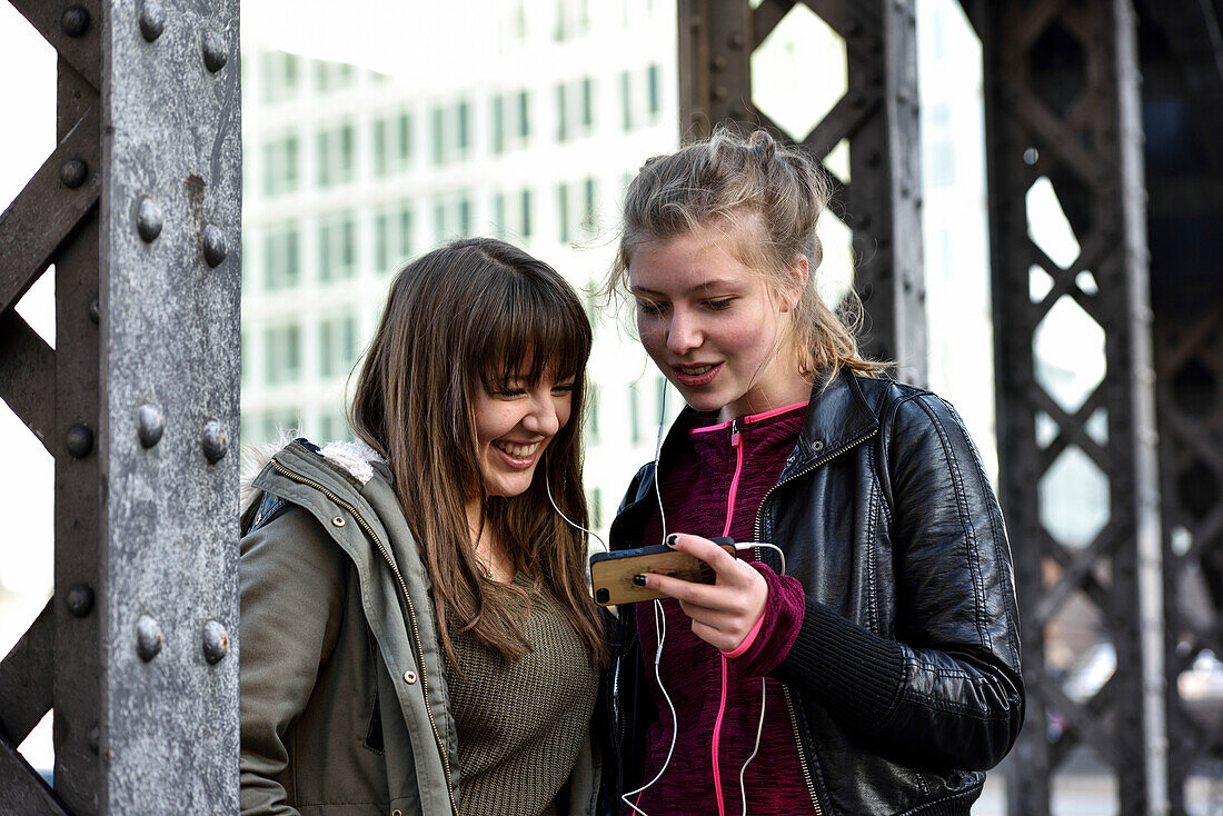 Mädchen hören Musik mit Kopfhörer draußen in der Speicherstadt, Hamburg, Deutschland, Europa