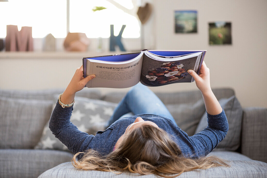 Mädchen liest auf dem Sofa, Hamburg, Deutschland, Europa