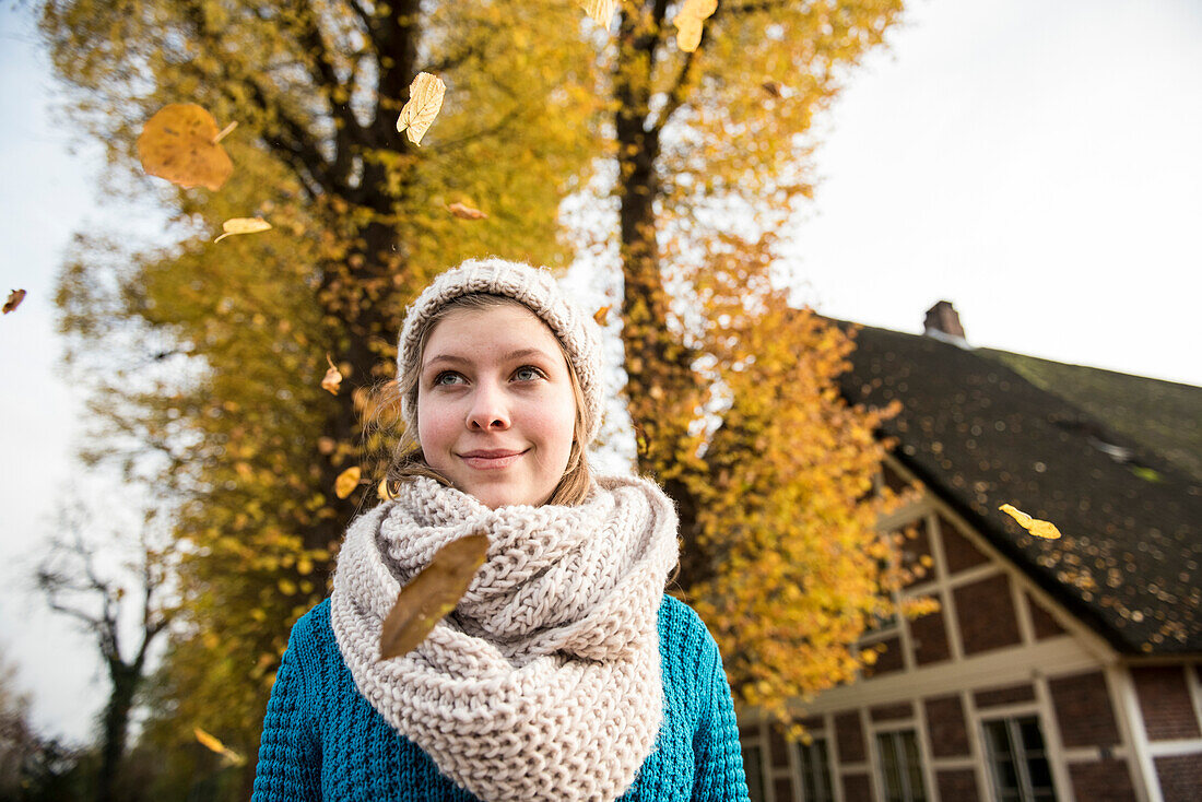 Teenage girl in an Autumn forest inside swirling foliage, Hamburg, Germany, Europe