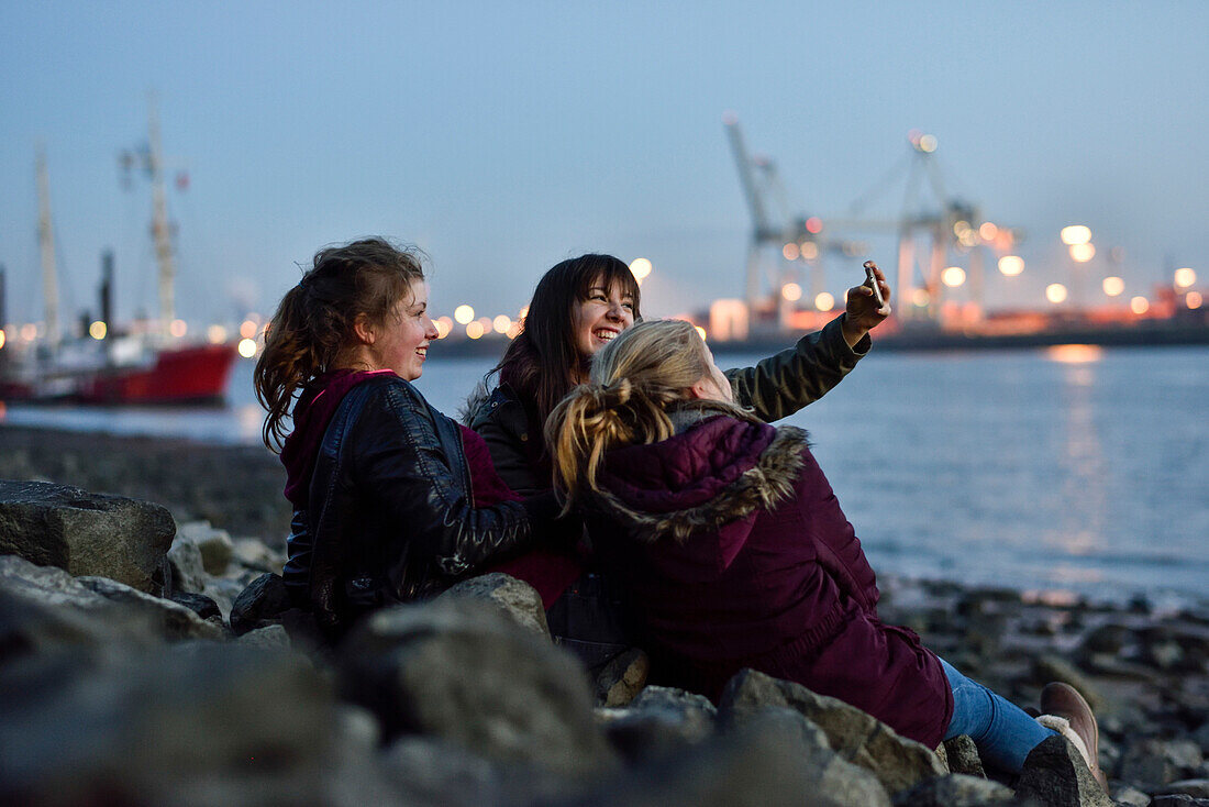 3 girls making selfie pictures at the Elbe River beach, Oevelgoenne, Hamburg, Germany, Europe