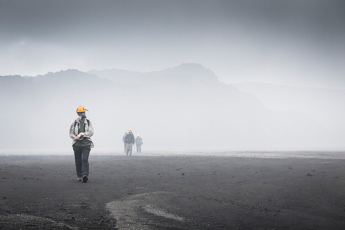Members of the expedition with helmets and gas mask walking through toxic gases of volcanoes Marum and Benbow, Vanuatu, Ambrym Island, South Pacific