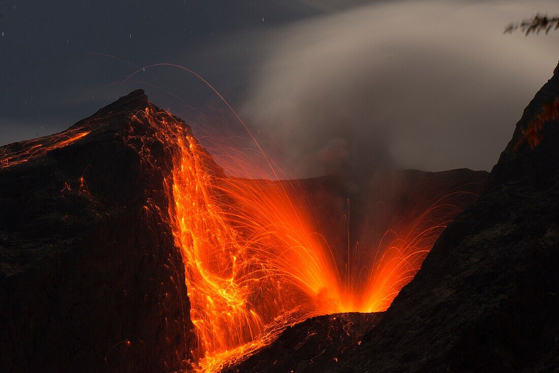 Nahaufnahme einer gewaltigen Eruptionen mit Lavabombenauswurf bei Nacht mit Sternenhimmel des Vulkans Batu Tara. - Indonesien, Insel Komba, Flores Sea