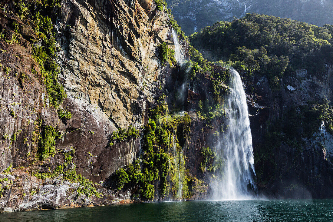 Waterfall over sheer cliffs to remote river, Te Anau, Southland, New Zealand