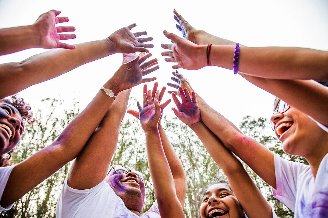 Low angle view of friends covered in pigment powder cheering