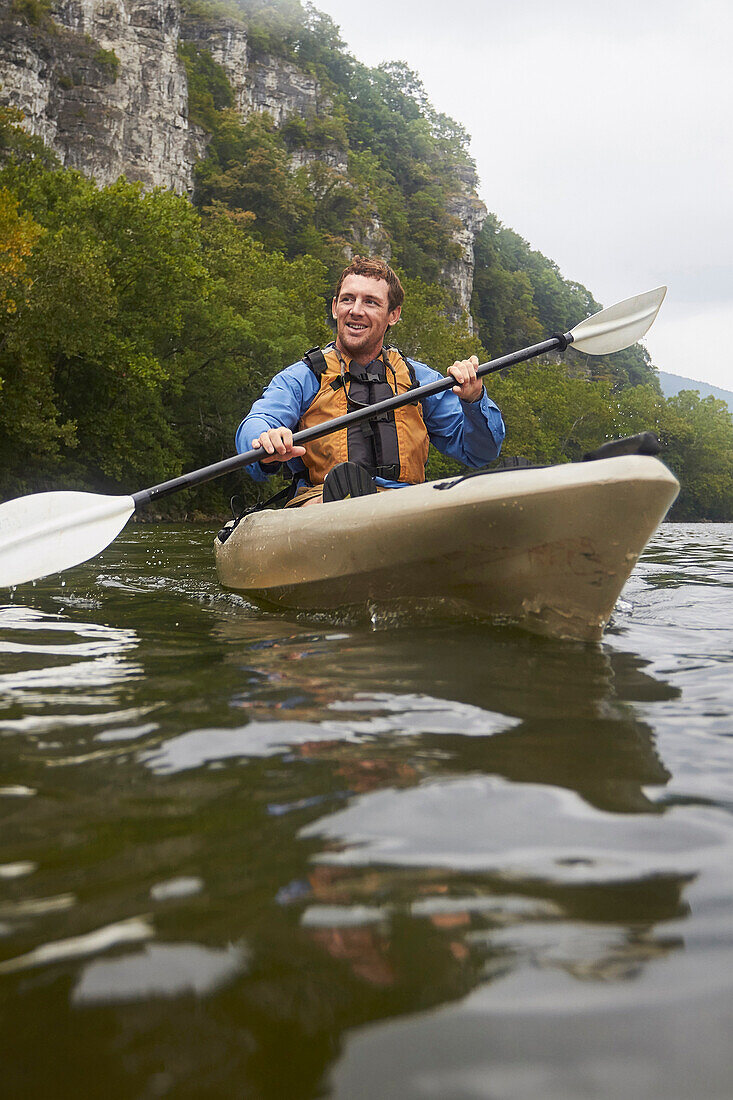 Caucasian man paddling kayak on remote river