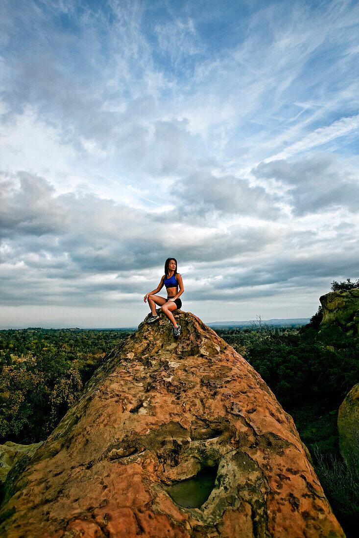 Vietnamese woman sitting on rocky hilltop