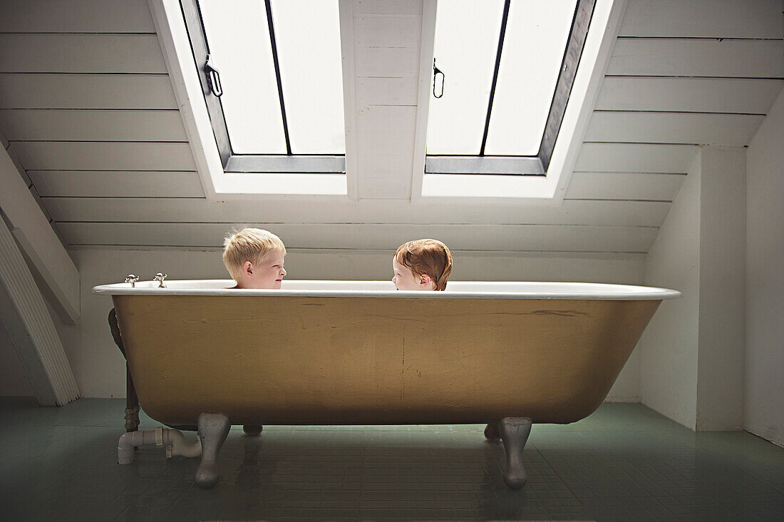 Caucasian brothers sitting in bathtub