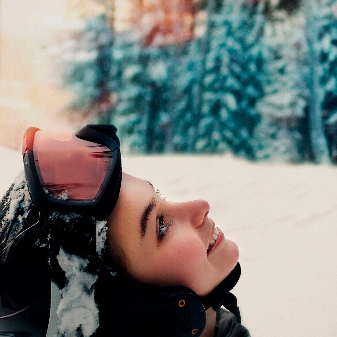 Caucasian snowboarder wearing goggles and helmet looking up