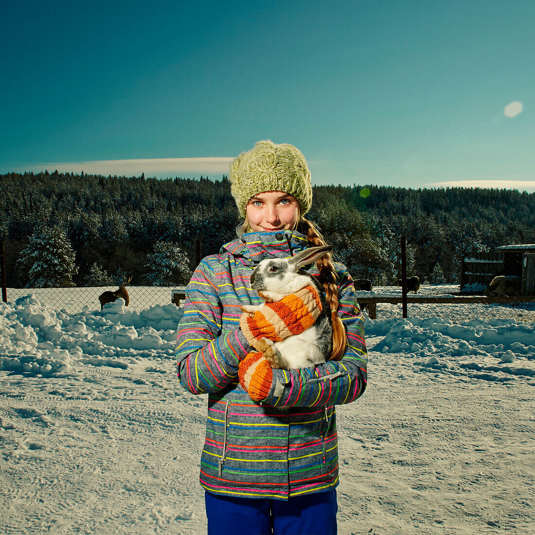 Caucasian girl hugging rabbit in snowy field