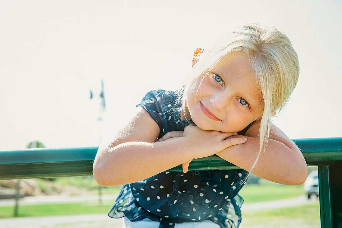 Caucasian girl leaning on farm fence