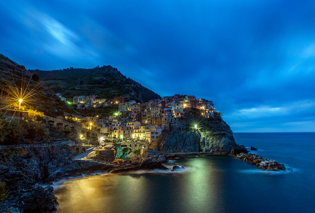 Rocky Manarola coastline illuminated at night, La Spezia, Italy
